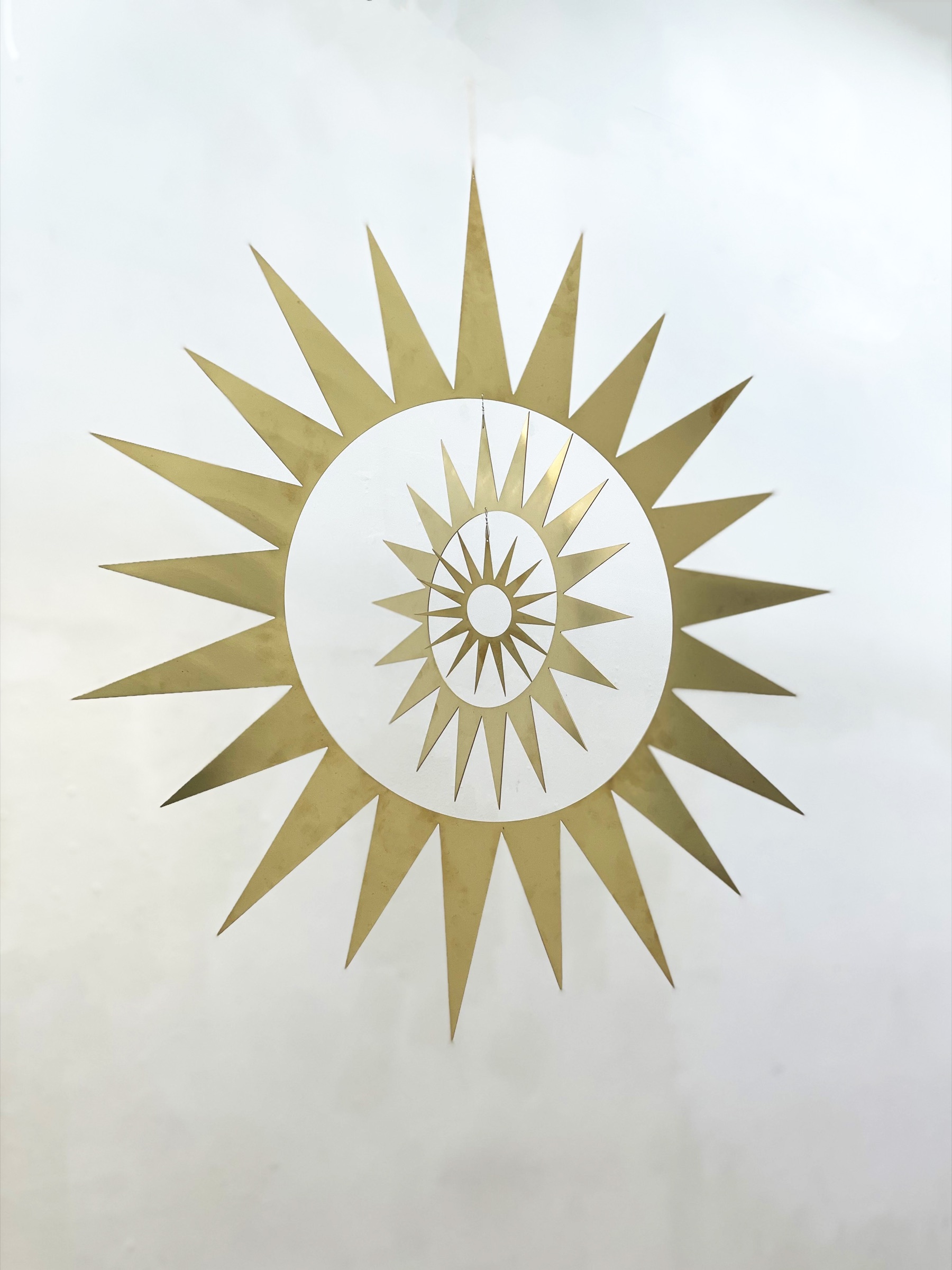 The sun, a suspended spiral of nested brass sun forms
